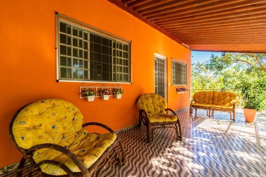 Varanda laranja da Casa Lírio com cadeiras de vime e vista para o jardim